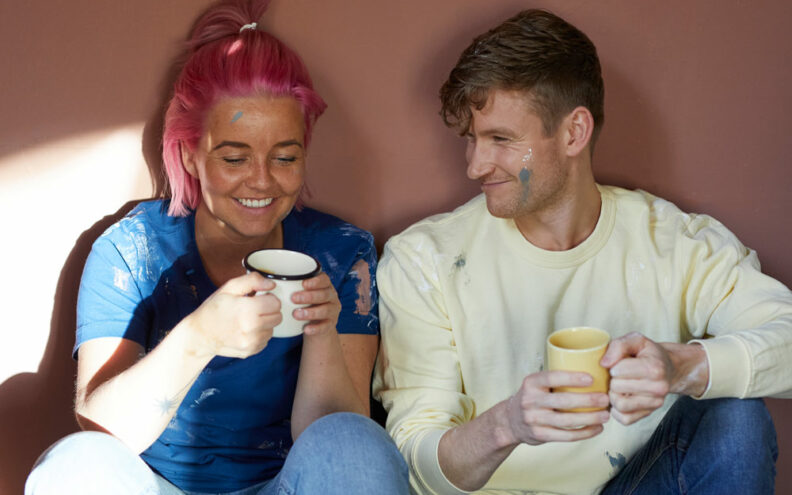 To personer som tar seg en pause fra malingen og nyter en kopp kaffe