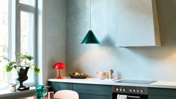 Et kjøkken med blå kjøkkenfronter og kalkmalte vegger